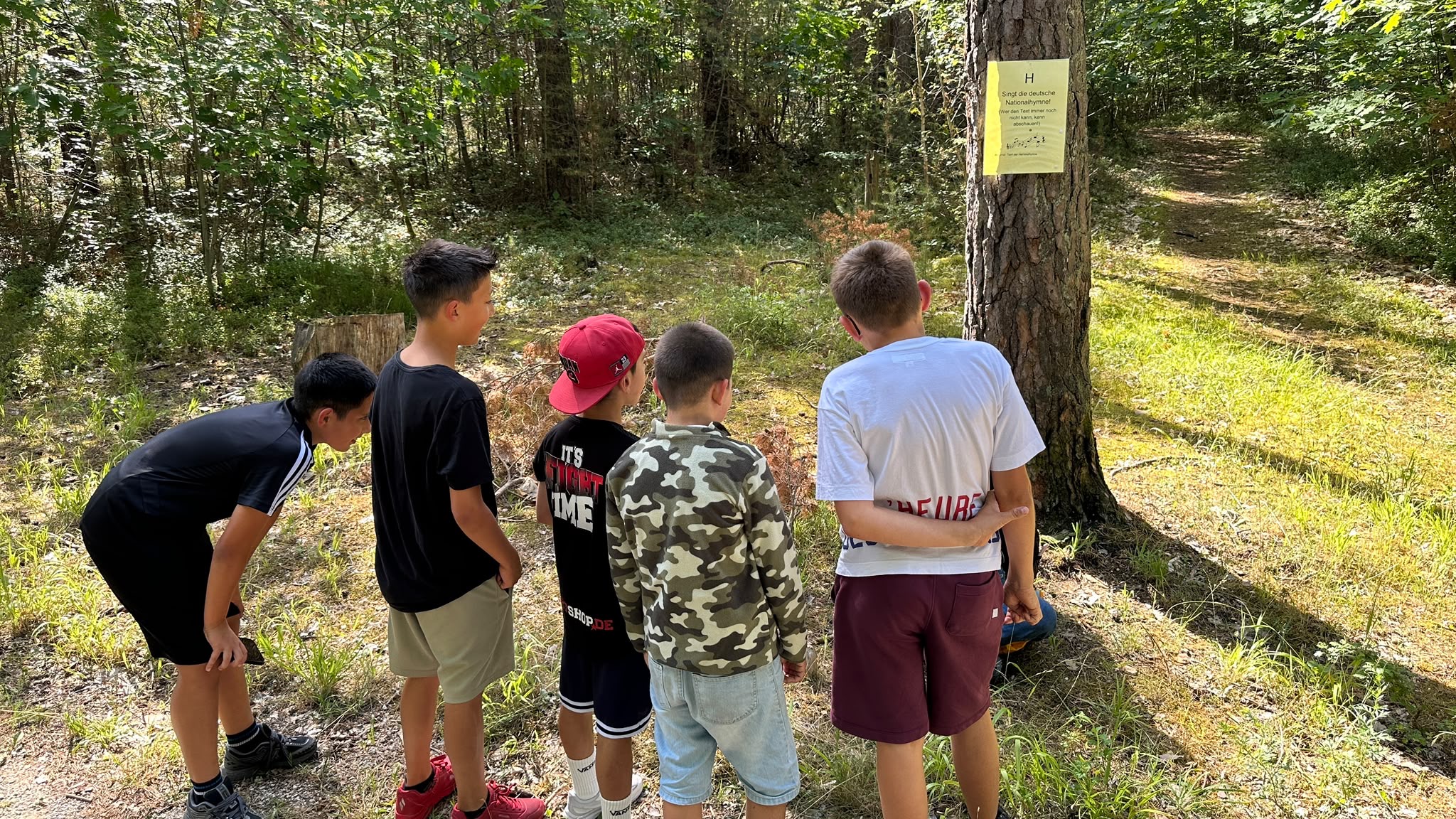Eine Schülergruppe betrachtet von hinten eine Aufgabenstation im Reichswald.